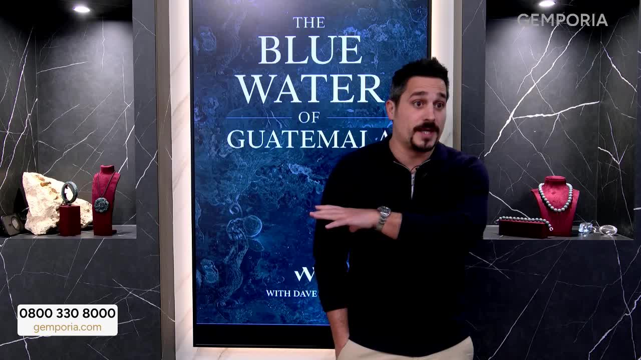 A man in a black shirt gestures toward a screen advertising "The Blue Water of Guatemala" on Gems TV. Jewelry is displayed in niches on either side of the presenter.
A man in a black shirt gestures toward a screen advertising "The Blue Water of Guatemala" on Gems TV. Jewelry is displayed in niches on either side of the presenter.