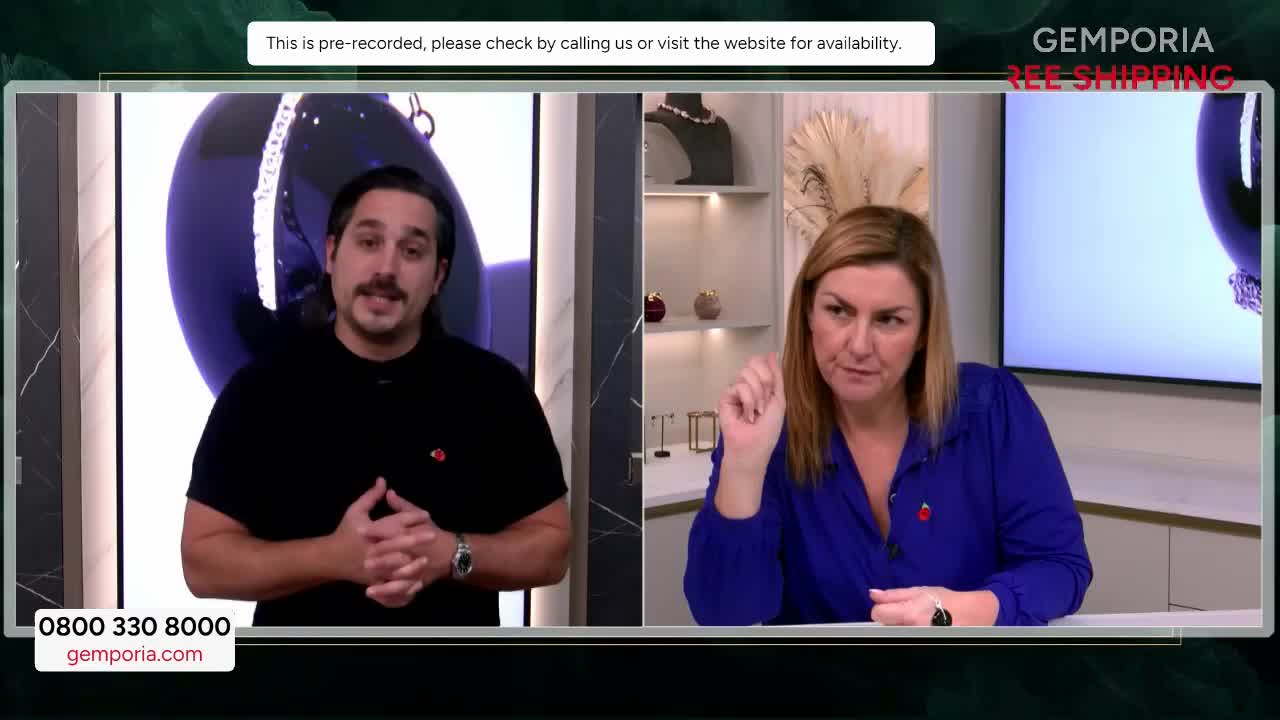 The man on the left is speaking directly to the camera, while the woman on the right gestures with her index finger. They're on a Gems TV show, with a large screen behind them displaying jewelry.
The man on the left is speaking directly to the camera, while the woman on the right gestures with her index finger. They're on a Gems TV show, with a large screen behind them displaying jewelry.