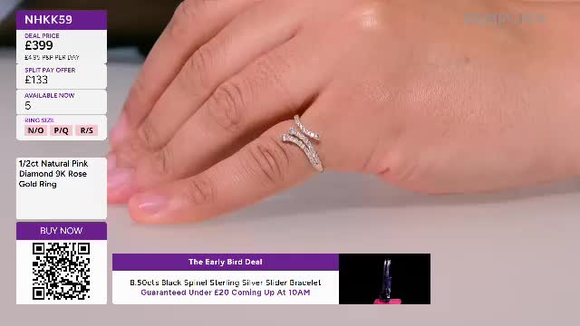 A hand, adorned with a delicate, twisting diamond ring, rests on a pale surface. On the screen, the ring is highlighted with its price and details as part of a Gems TV presentation.