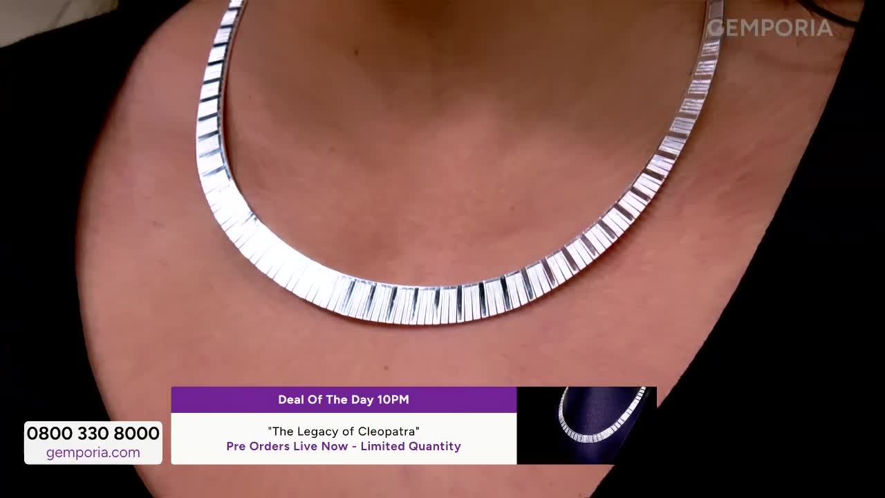 A striking silver necklace, its segments catching the light, rests against a dark top. A graphic overlay announces a "Deal of the Day 10PM" for "The Legacy of Cleopatra" collection.