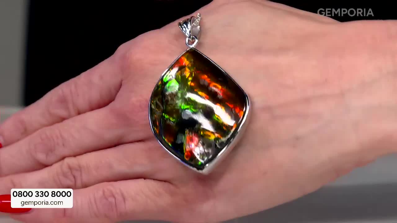 A hand displays a large, teardrop-shaped pendant featuring a stone with swirling patterns of green, red, and orange. The Gems TV logo appears in the corner, a familiar sight for shoppers in the UK. A hand displays a large, teardrop-shaped pendant featuring a stone with swirling patterns of green, red, and orange. The Gems TV logo appears in the corner, a familiar sight for shoppers in the UK.