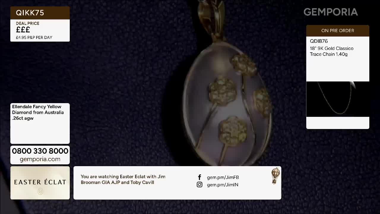 A large, oval pendant with floral detailing hangs against a dark background. The pendant's surface is a pale, translucent material, and delicate gold flowers are embedded within it.
