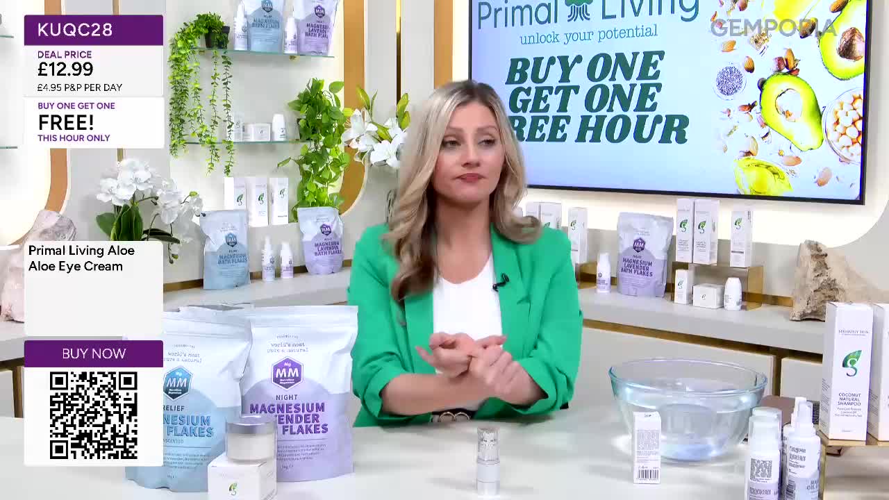 A woman in a bright green jacket is demonstrating a product on Gems TV. She's holding a small bottle in her hands, and a large bowl of water sits in front of her.