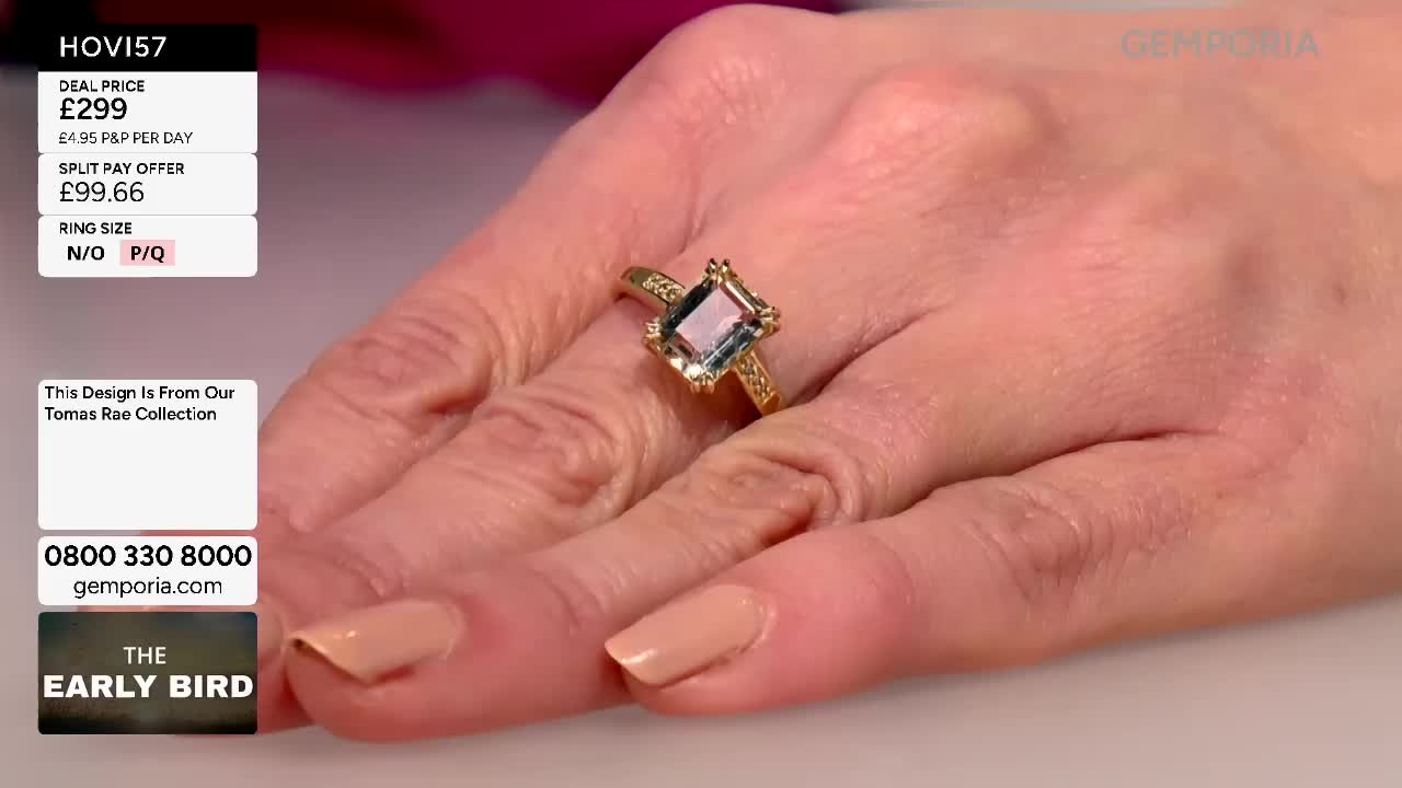 A hand displays a gold ring with a rectangular blue stone, its facets catching the light. The ring, part of the Tomas Rae collection, is being presented on Gems TV. A hand displays a gold ring with a rectangular blue stone, its facets catching the light. The ring, part of the Tomas Rae collection, is being presented on Gems TV.