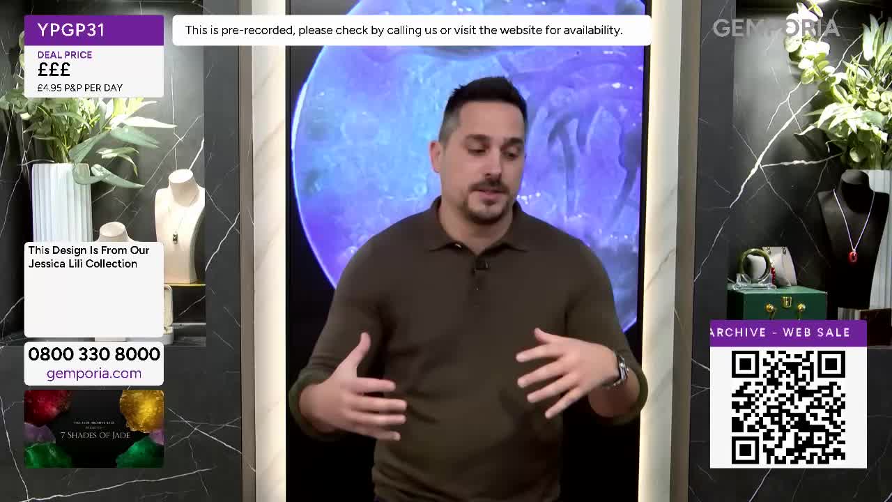 A man in a brown polo shirt gestures with his hands as he speaks. Behind him, a large, circular screen displays a swirling blue image. A man in a brown polo shirt gestures with his hands as he speaks. Behind him, a large, circular screen displays a swirling blue image.