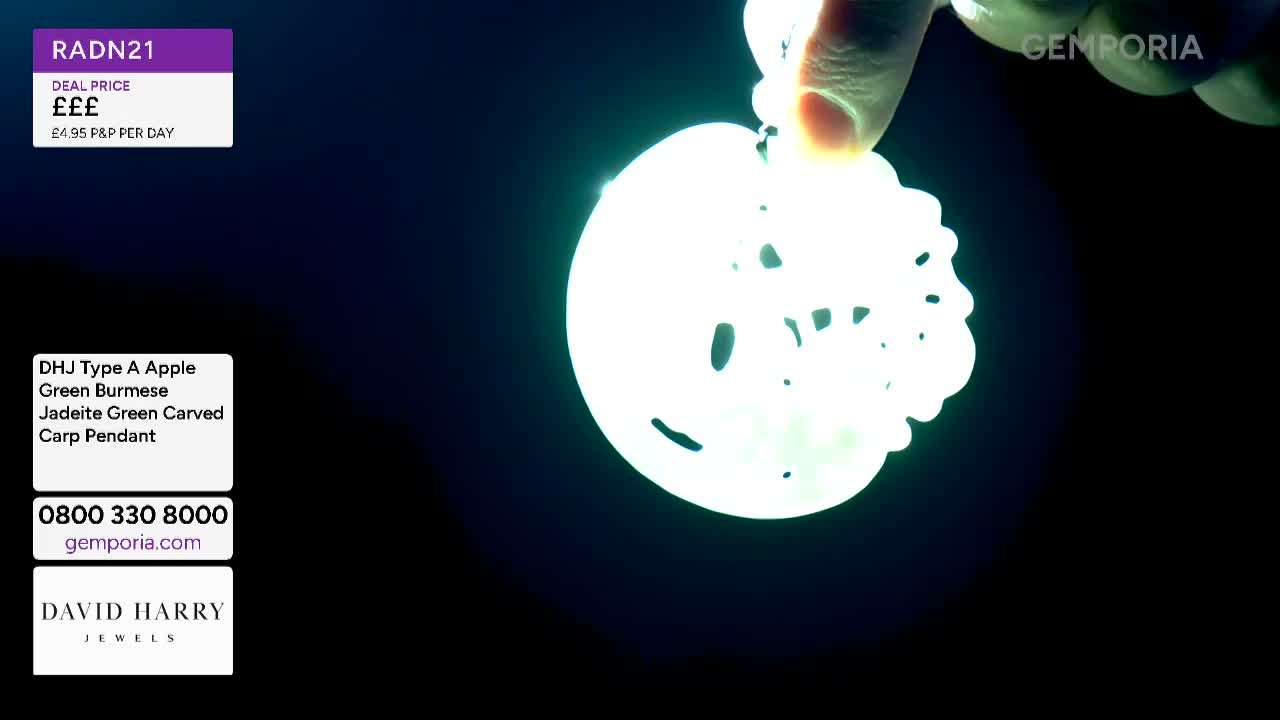 A finger holds up a bright, white pendant carved with a carp design. The pendant glows intensely against the dark background, almost obscuring its intricate details. A finger holds up a bright, white pendant carved with a carp design. The pendant glows intensely against the dark background, almost obscuring its intricate details.