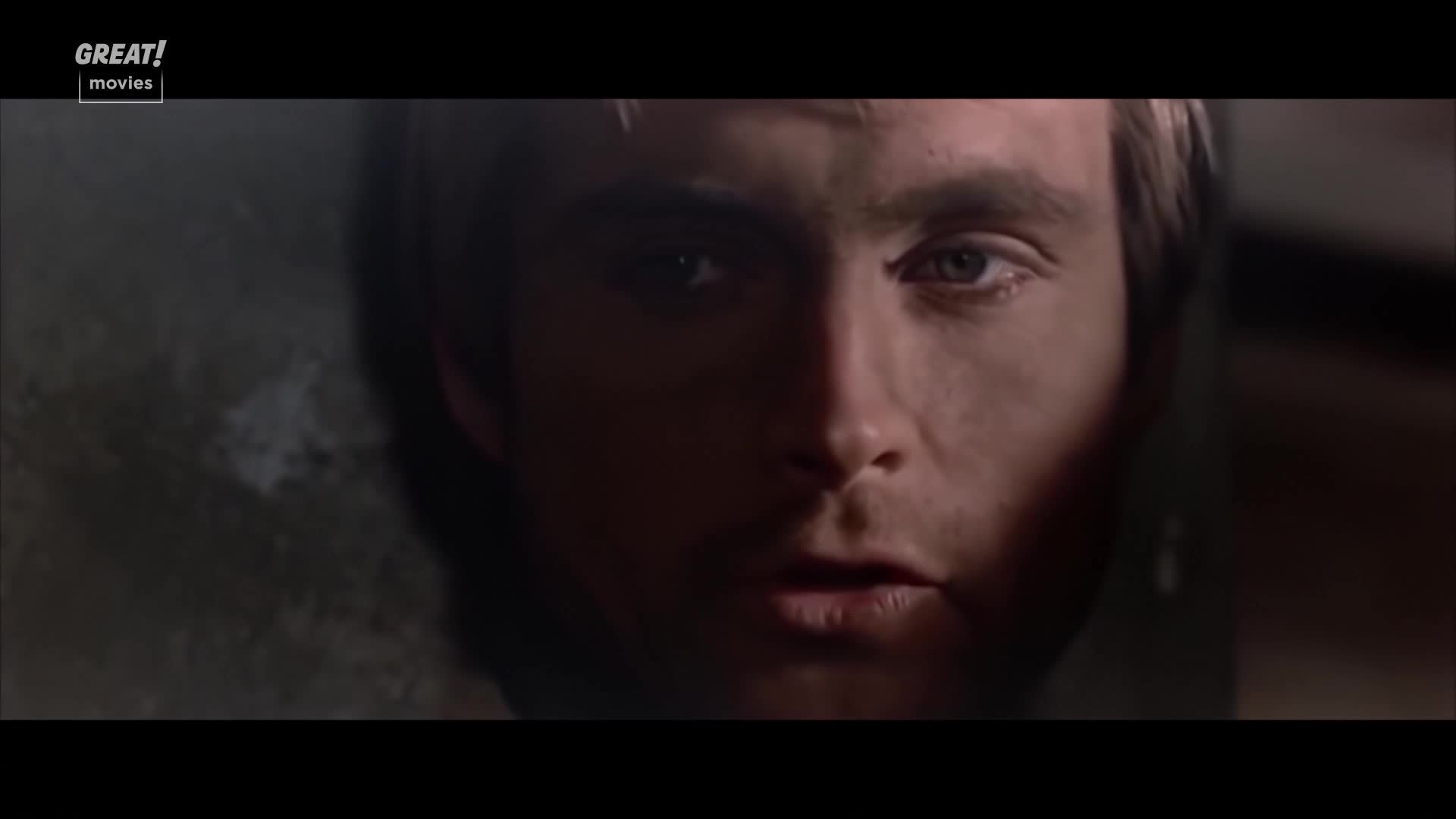 The man's face is mostly in shadow, with the light catching his eye and the side of his nose. His mouth is slightly open, as if he's about to speak.
