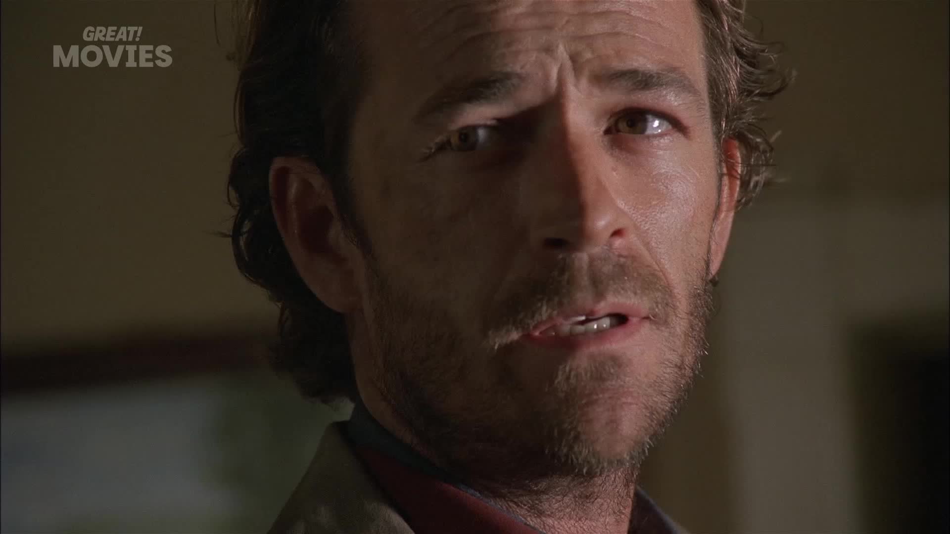 A man's face fills the frame, his eyes wide with a look of distress. He's speaking, his mouth slightly open, as if caught mid-sentence.