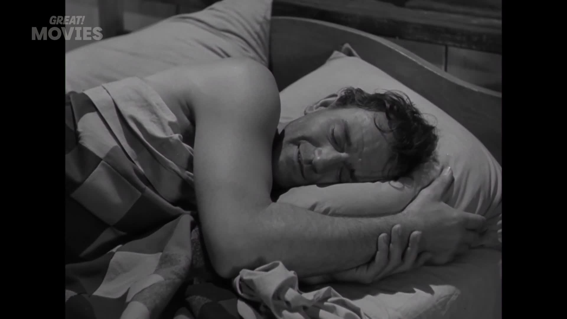 A man sleeps soundly, his arm tucked under his head. The patterned duvet is pulled up to his chin, a familiar sight in any British bedroom.