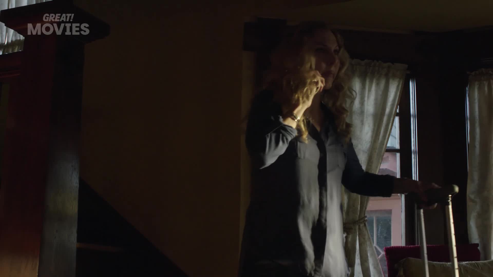 A woman with curly blonde hair stands by a window, holding a cane and talking on her phone. The "GREAT! MOVIES" logo is visible in the upper left corner.