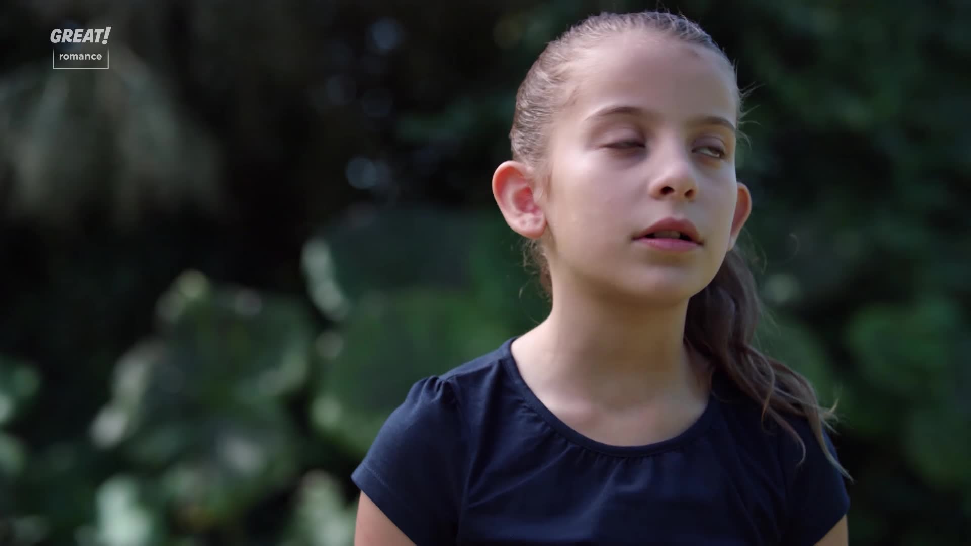 A young girl with her eyes closed is bathed in soft, natural light. She seems lost in thought, a slight smile playing on her lips.
