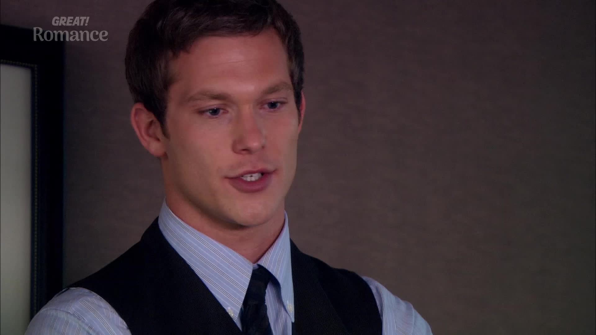 The man in the suit is speaking, his mouth open as he forms words. His expression is earnest, and he seems to be making a point.

