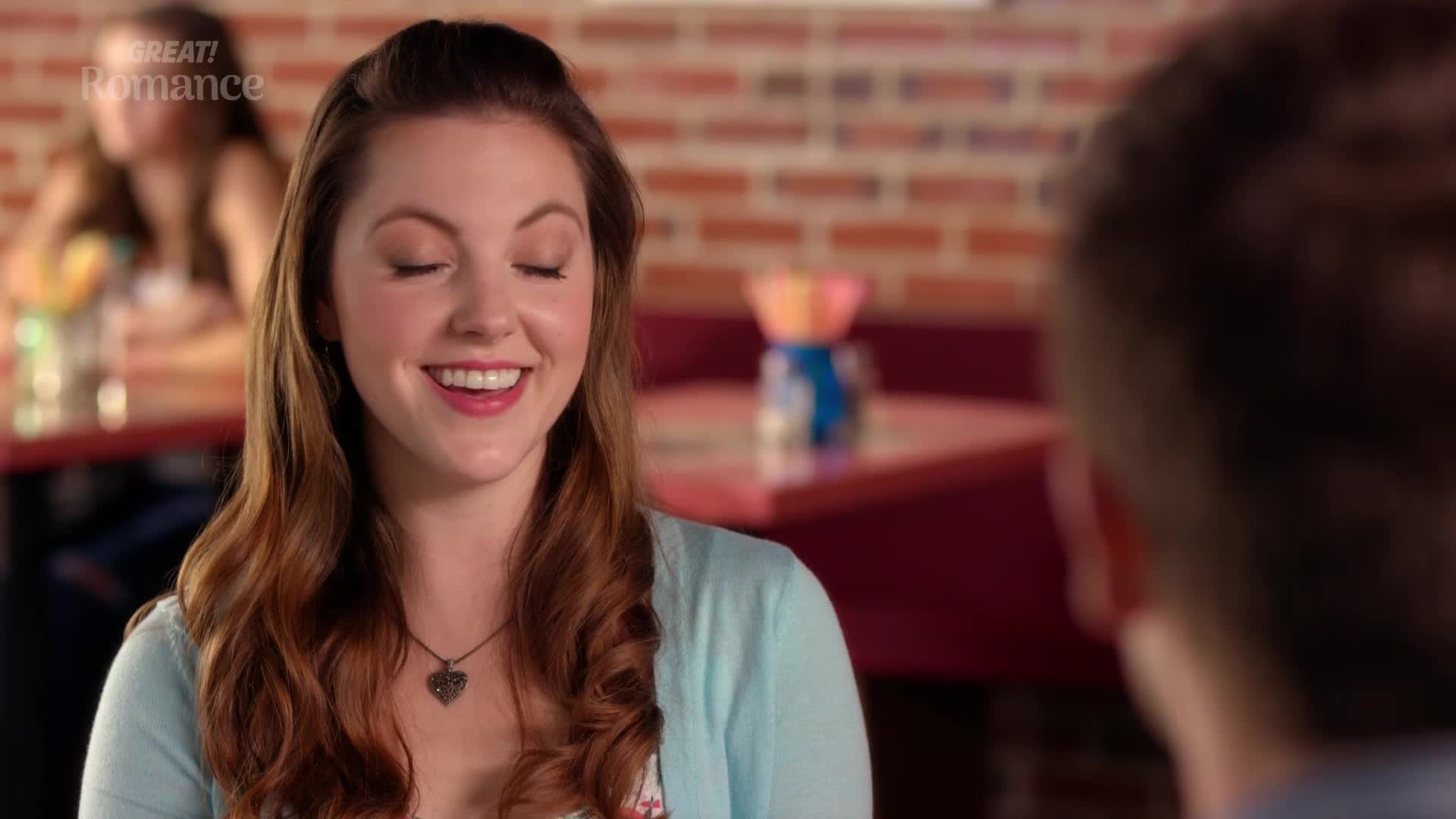 A young woman with auburn hair laughs, her eyes closed, across from a man whose back is turned. The background suggests a casual cafe setting, perhaps in the UK, with a hint of a romantic encounter. A young woman with auburn hair laughs, her eyes closed, across from a man whose back is turned. The background suggests a casual cafe setting, perhaps in the UK, with a hint of a romantic encounter.