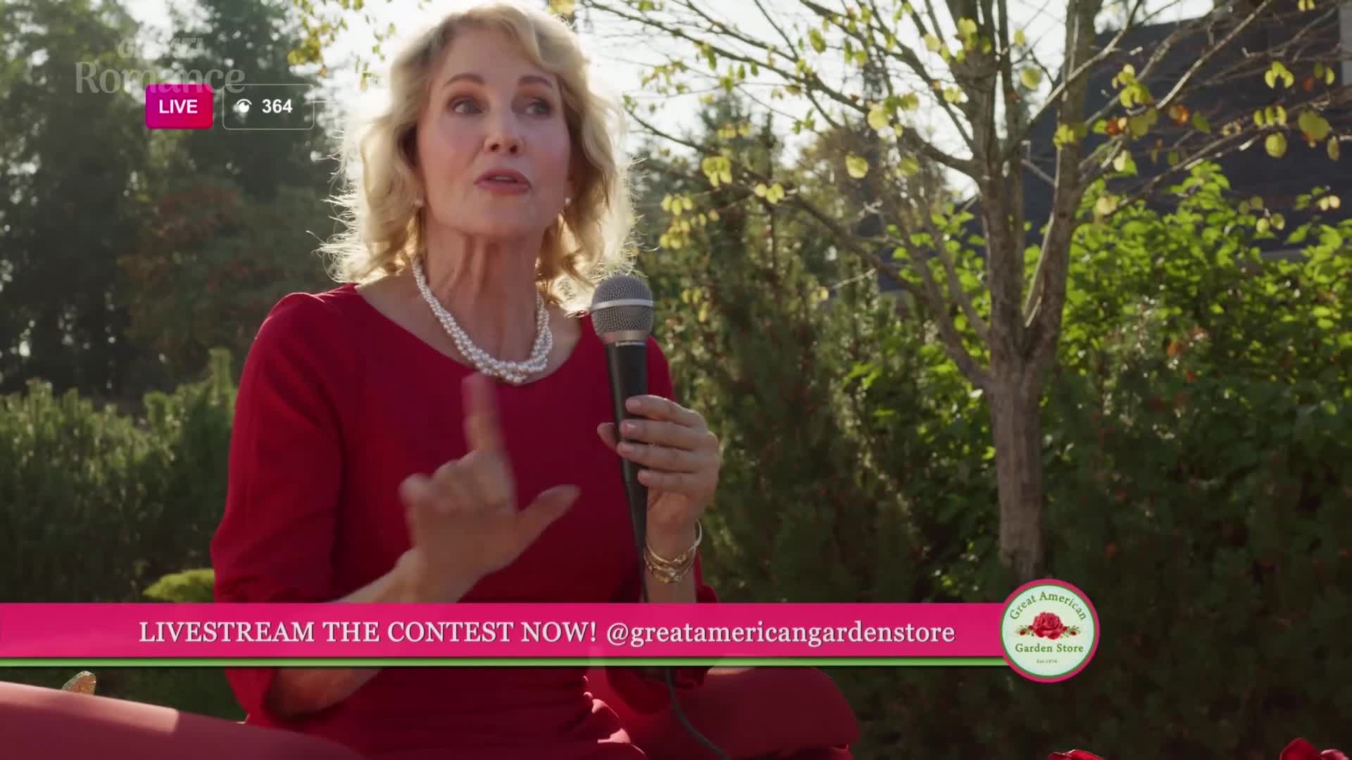 A woman in a red dress speaks into a microphone, gesturing with her left hand. A banner below her reads "LIVESTREAM THE CONTEST NOW!"