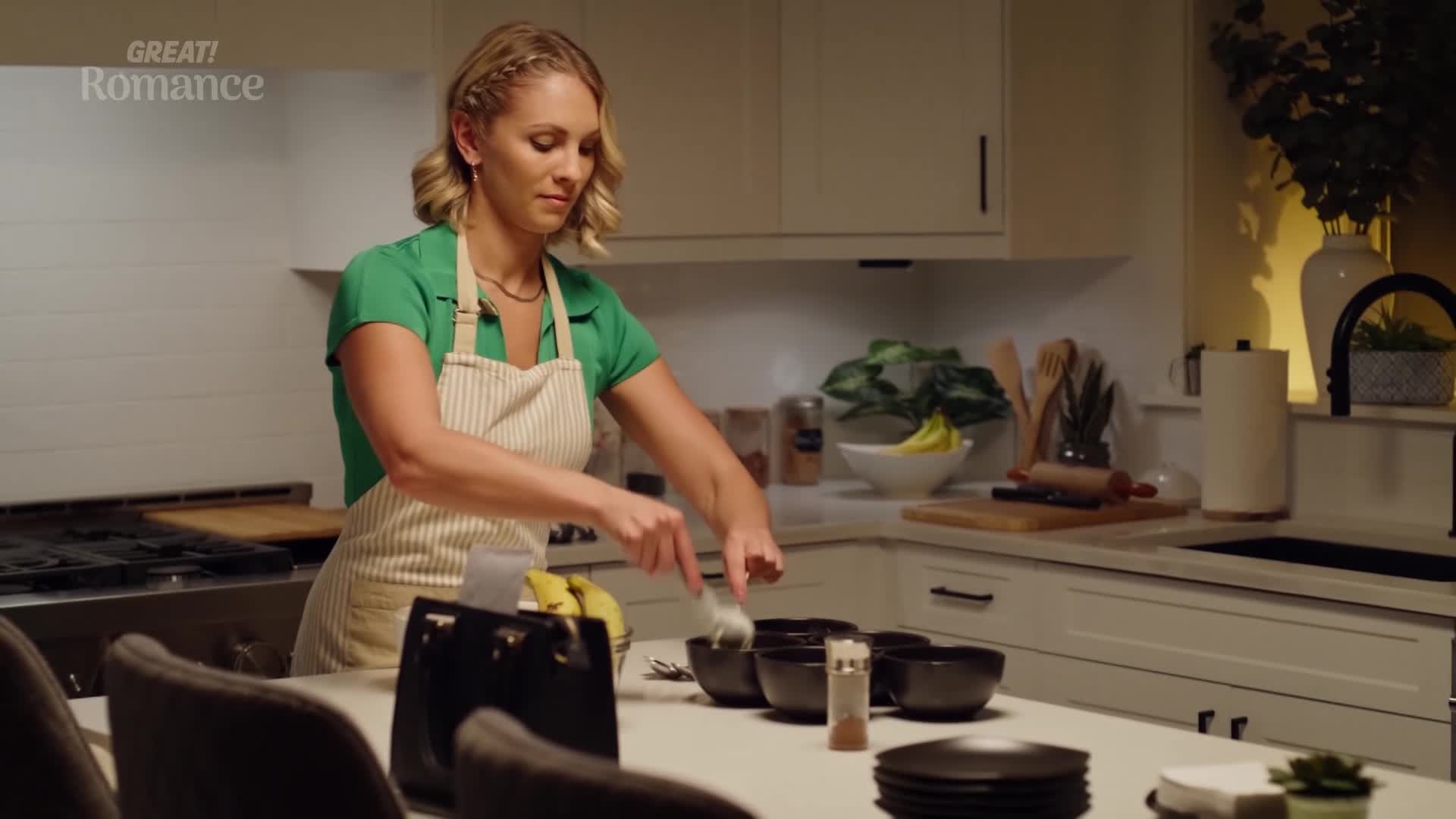 A woman in a green top and apron is busy in her kitchen, scooping something into a row of black bowls. The scene feels like a quiet moment before a meal, perhaps a special occasion.