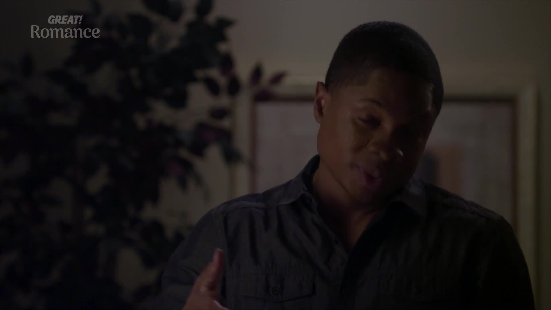 A young man in a dark shirt gestures with his left hand, his mouth open as if speaking. The "GREAT! Romance" logo appears in the upper left corner.