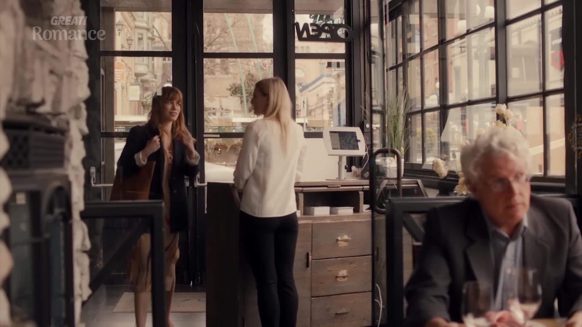 A woman with auburn hair enters a cafe, her expression hopeful. Another woman, in a white jacket, stands behind the counter, ready to serve. A woman with auburn hair enters a cafe, her expression hopeful. Another woman, in a white jacket, stands behind the counter, ready to serve.