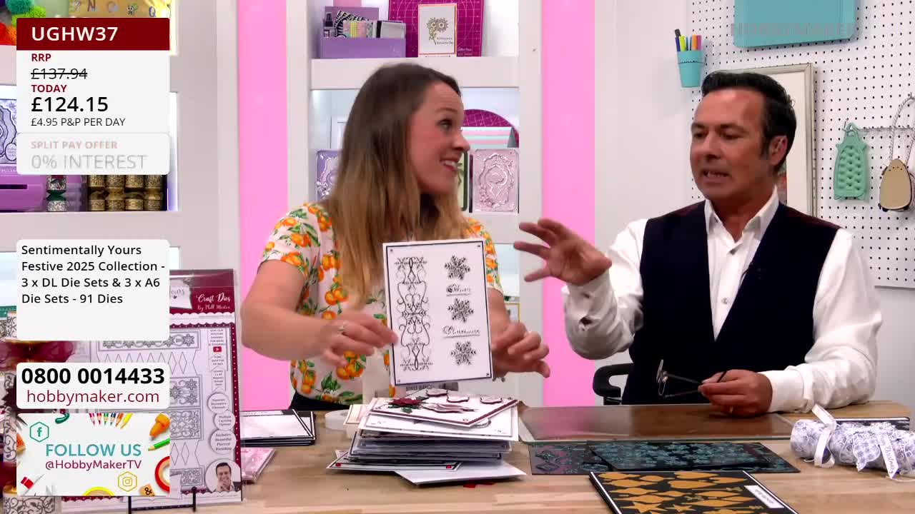 The woman holds a card displaying die-cut designs, while the man gestures expansively with his hands. They're likely demonstrating products from Hobby Maker, a UK-based retailer.
