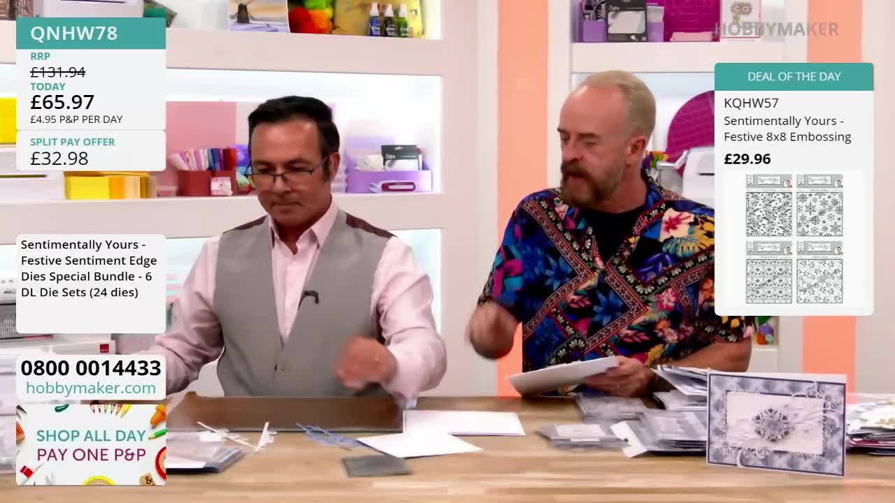 A man in a patterned shirt gestures towards a display of crafting supplies. His colleague, wearing a vest, reaches into a cardboard box.
