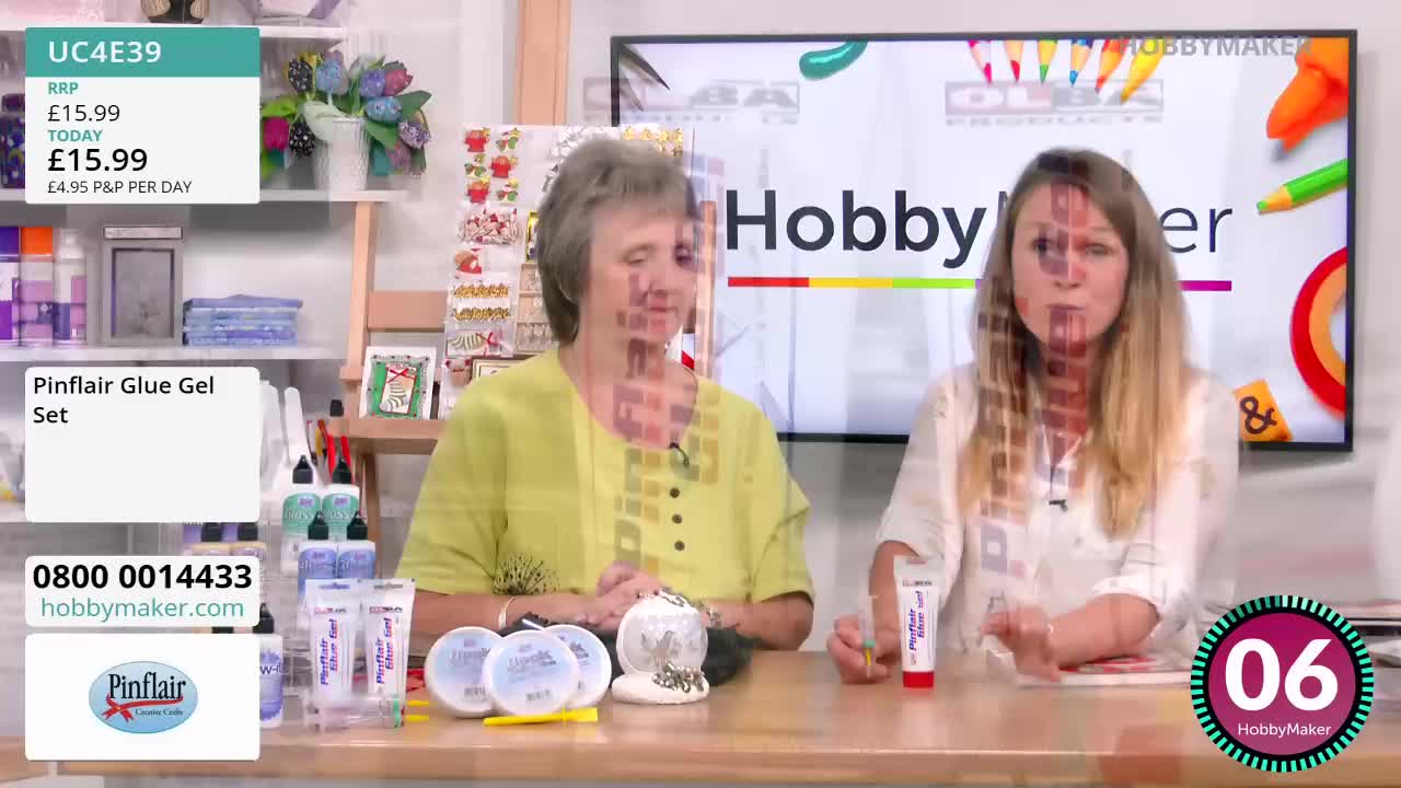 Two women are seated at a table, one holding a tube of Pinflair Glue Gel, while the other gestures towards a display of craft supplies. A Hobby Maker logo is visible on the screen behind them, with a countdown clock ticking down.
