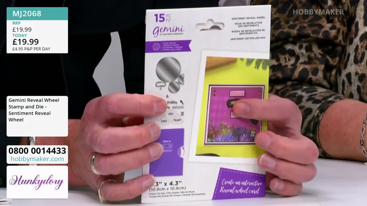 A person holds a Gemini craft kit from Hobby Maker, showing the front of the packaging. The kit features a "Sentiment Reveal Wheel" and a sample card with a purple background.
