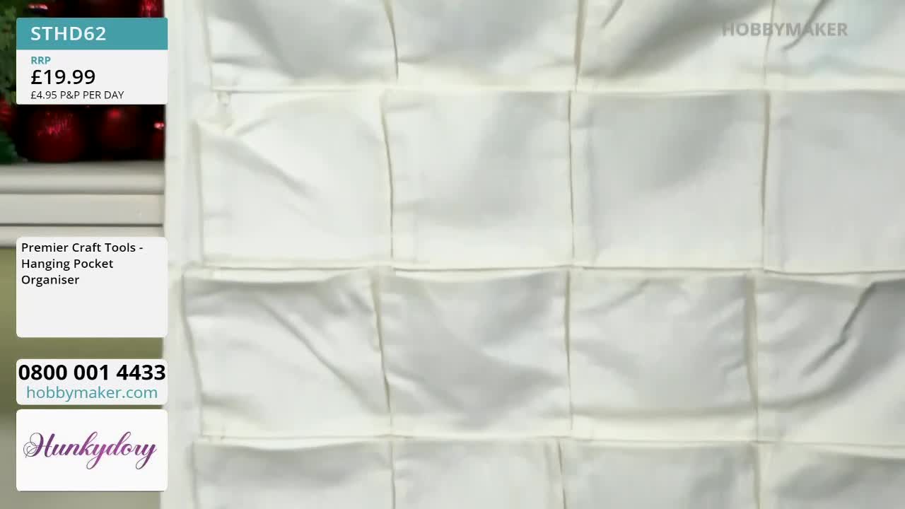 A cream-colored hanging pocket organizer from Hobby Maker dominates the frame. The pockets are empty, their fabric slightly rumpled.
