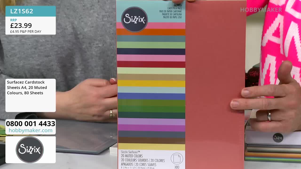A person on Hobby Maker holds a pack of Sizzix cardstock, showcasing the muted colors. The presenter points to the cardstock's solid, reddish-brown side.
