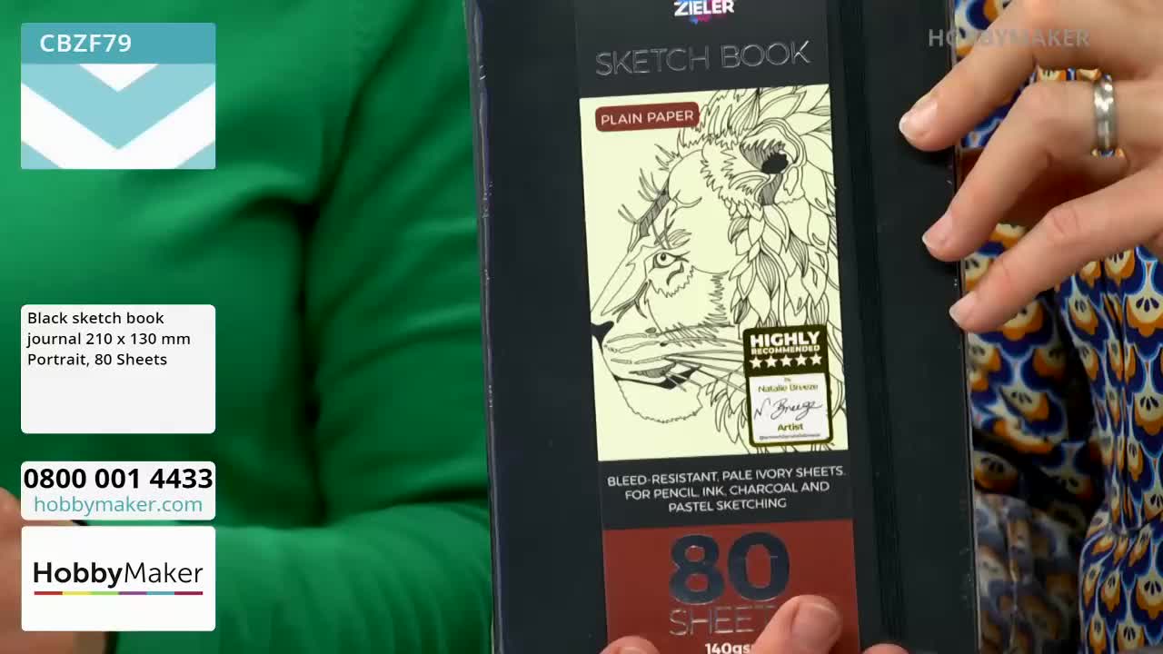 A hand with a silver ring turns the cover of a black sketch book featuring a detailed lion illustration. The book is from HobbyMaker, a UK-based company.