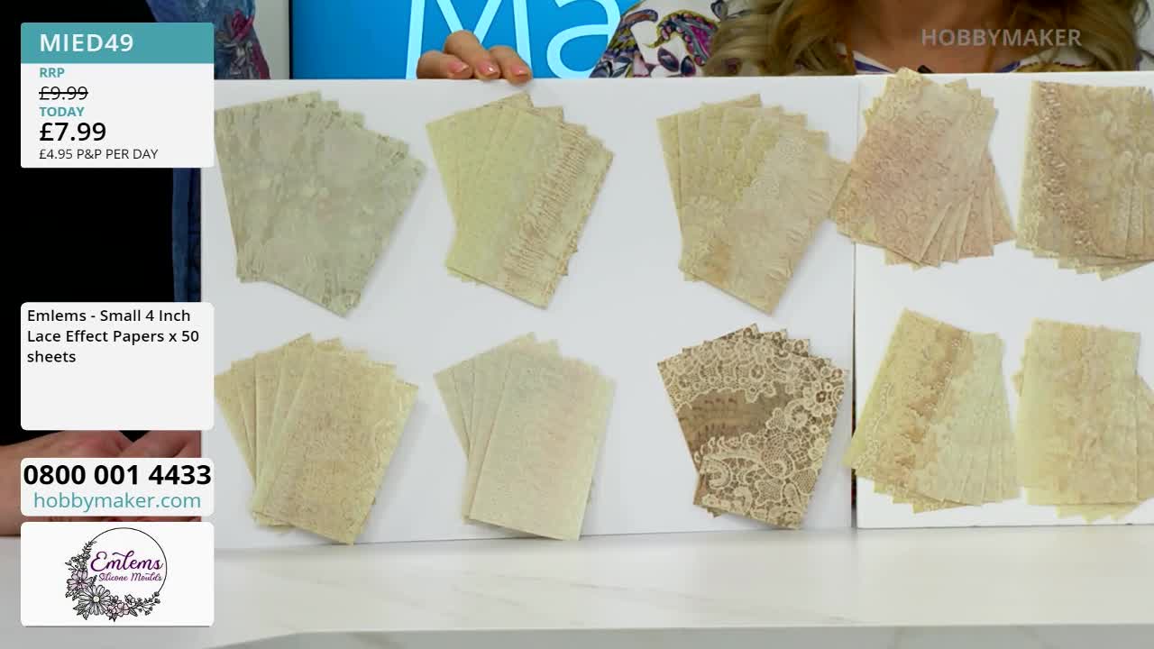 A hand is arranging stacks of delicate, lace-patterned paper on a white surface. The papers, in varying shades of cream and beige, are fanned out to display their intricate designs.