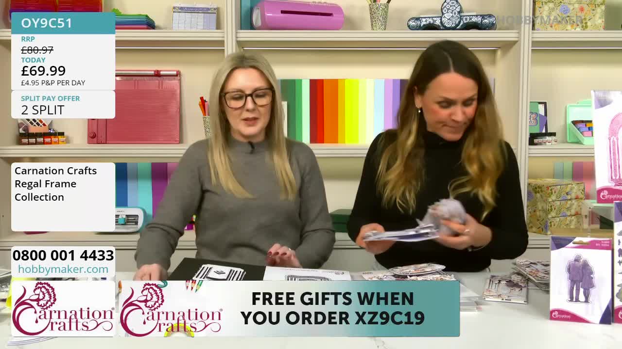 The woman on the right is holding up a small, light-coloured bundle of craft supplies. The woman on the left gestures towards a black album on the table.