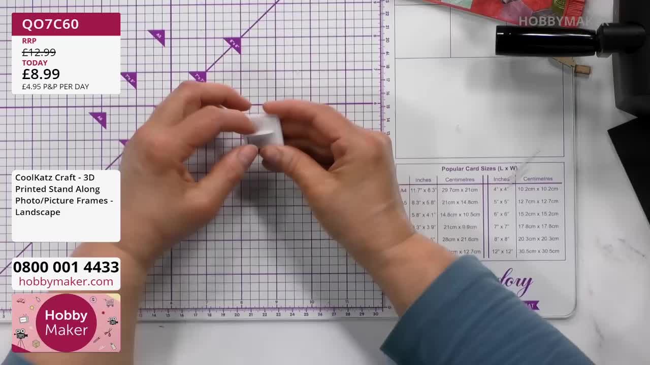 Fingers carefully fold a small white piece of card. This is part of a 3D printed stand for a photo frame, available from Hobby Maker.