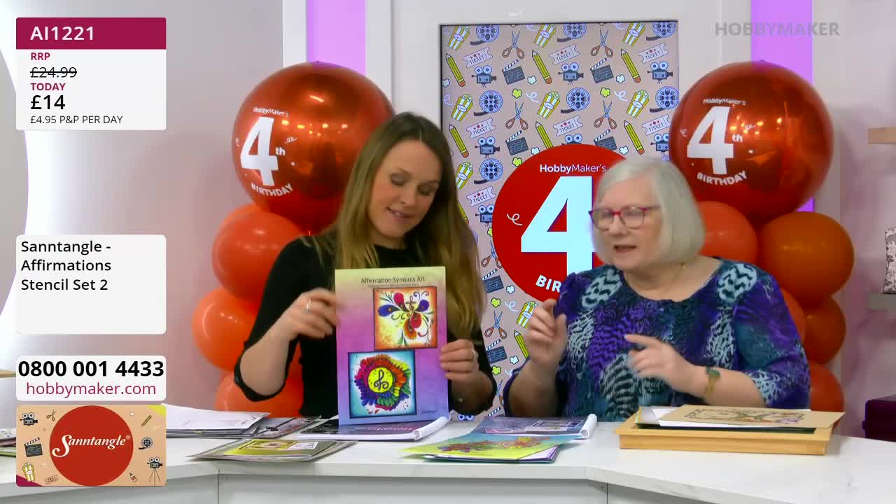 A woman in a black top holds up a colourful craft stencil set, while a woman in a patterned blouse gestures animatedly. Behind them, large orange balloons celebrate HobbyMaker's 4th birthday. A woman in a black top holds up a colourful craft stencil set, while a woman in a patterned blouse gestures animatedly. Behind them, large orange balloons celebrate HobbyMaker's 4th birthday.