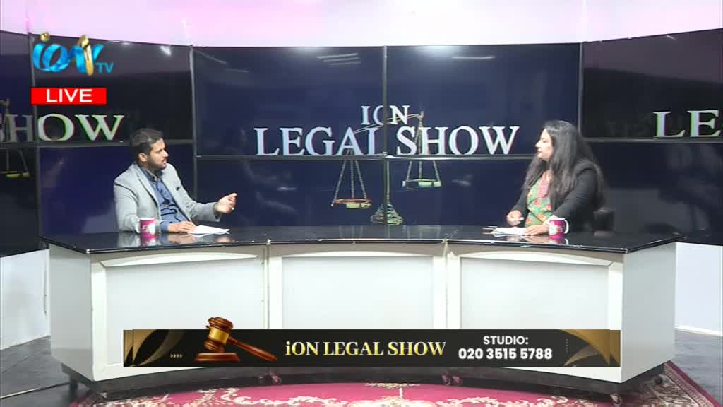 On the set of Ion TV's "Legal Show," two people sit at a desk, engaged in conversation. The man gestures with his hands, while the woman listens, a mug in front of her.
