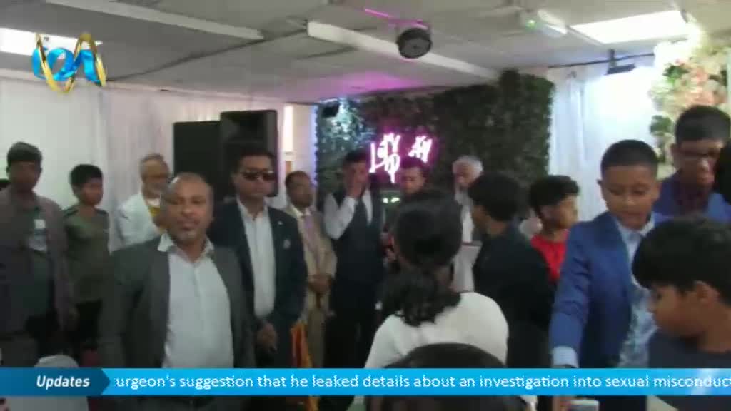A group of people, some in suits, are gathered in a room with a neon sign on the wall. The Ion TV logo is visible in the corner, with a news ticker running at the bottom of the screen.
