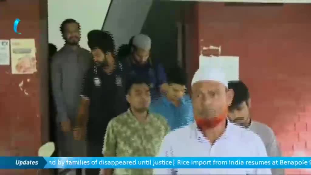 A group of men, some wearing white caps, are exiting a doorway. The camera focuses on a man with a red beard in the foreground.
