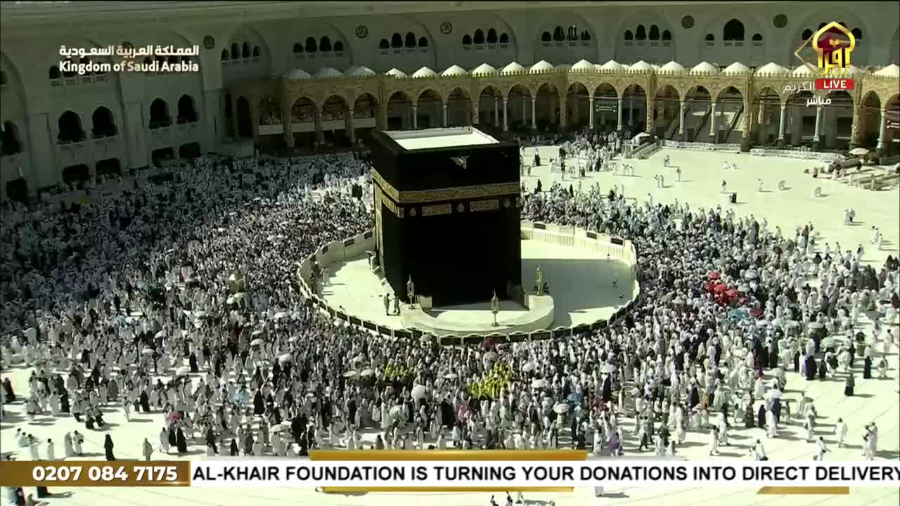 A sea of people, mostly in white, flows around the black cube at the center. The scene is broadcast live on Iqra TV from the Kingdom of Saudi Arabia.
