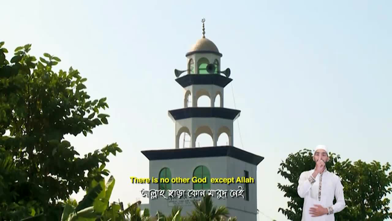 A man in a white robe gestures with his finger to his lips, while a mosque minaret rises behind him. Subtitles on the screen, likely from Iqra TV in the United Kingdom, display a religious statement.
