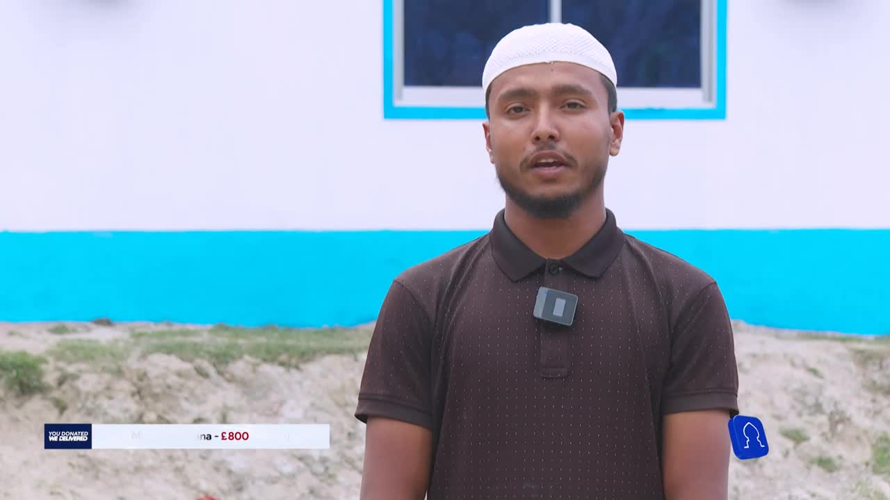 A man in a white cap and brown shirt stands in front of a white and blue building, speaking into a microphone. The Iqra TV logo, along with a donation amount, appears at the bottom of the screen.
