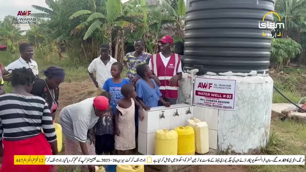 People are gathered around a newly built water well, filling yellow containers. A man in a red vest stands with a group of children, while the Islam Channel Urdu logo is visible in the corner.
