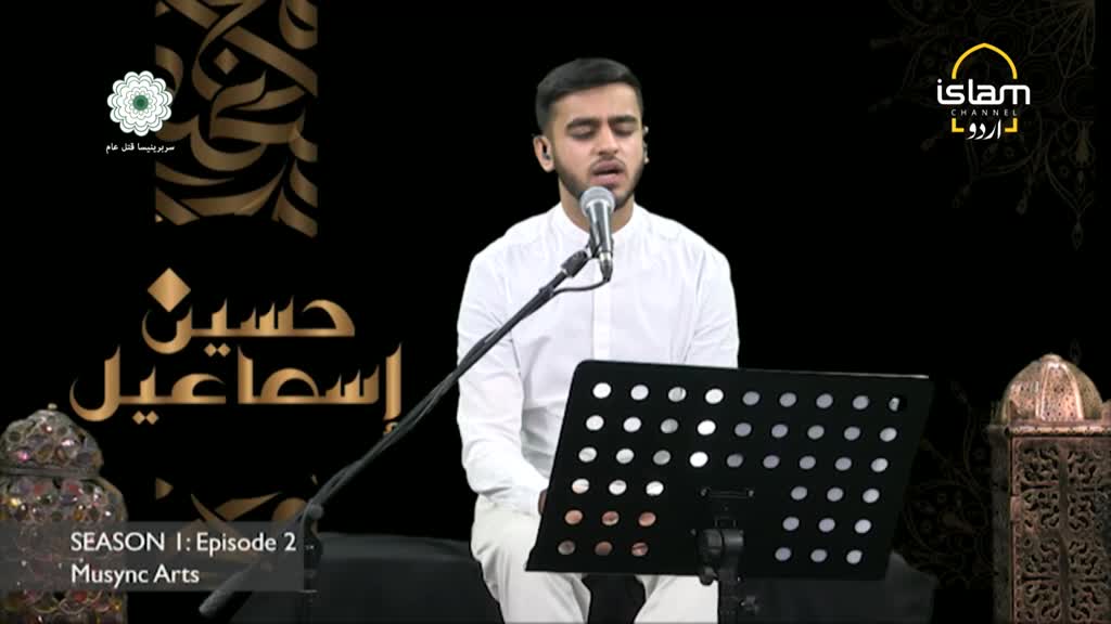 A young man in a white shirt sings into a microphone, his eyes closed. The set, likely for a program on Islam Channel Urdu in the United Kingdom, features decorative lanterns and calligraphy.
