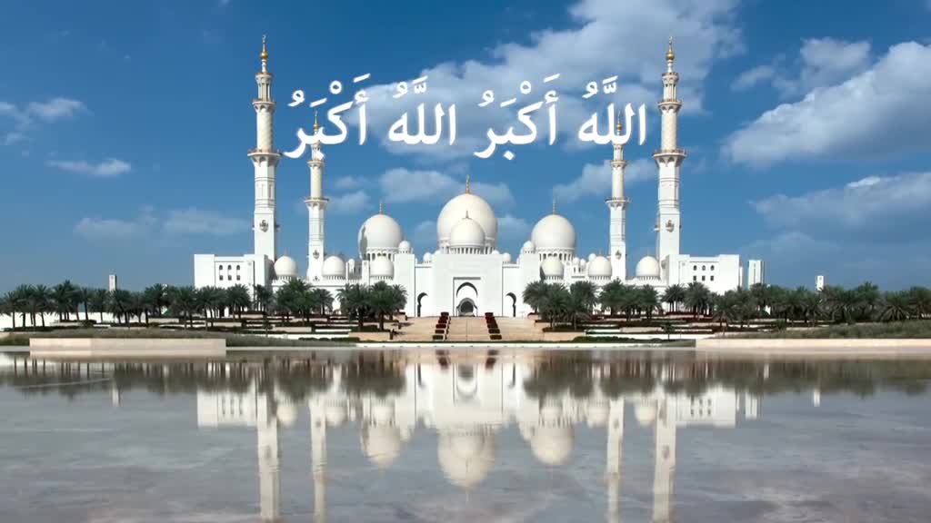 A grand white mosque rises against a bright blue sky, its reflection shimmering in the still water below. Above, the words "Allahu Akbar" are written in Arabic script.
