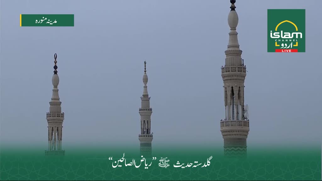 Three minarets, their cream-colored structures reaching into a hazy sky, dominate the view. The Islam Channel Urdu logo in the top right corner indicates a broadcast from the United Kingdom.
