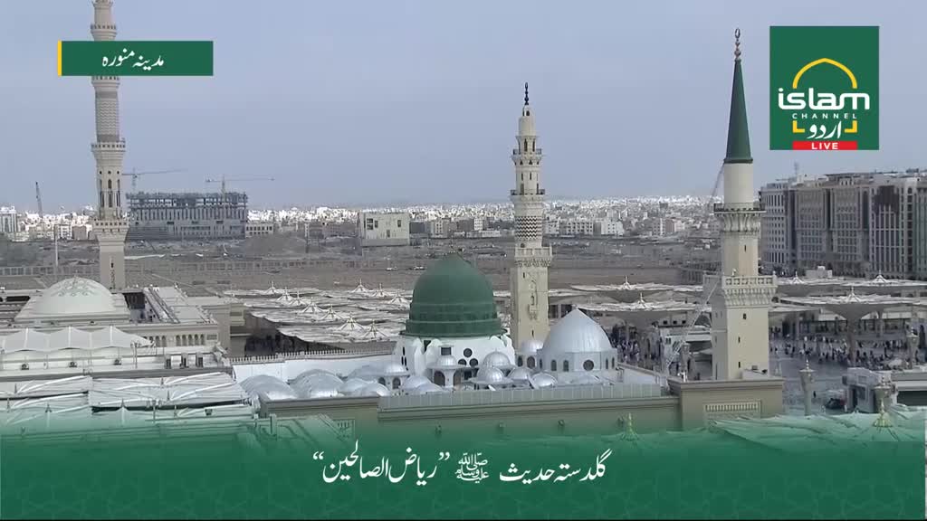 The camera offers a wide view of the mosque, its green dome and minarets standing out against the pale sky. The Islam Channel Urdu logo is visible, broadcasting from the United Kingdom.
