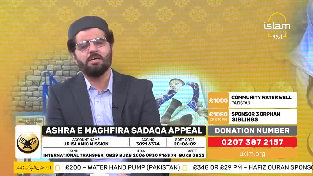 A man in a suit and kufi speaks into a microphone, his gaze directed forward. Behind him, a screen displays information about a fundraising appeal, including a photo of a child and donation details for the UK Islamic Mission. A man in a suit and kufi speaks into a microphone, his gaze directed forward. Behind him, a screen displays information about a fundraising appeal, including a photo of a child and donation details for the UK Islamic Mission.