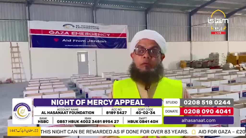 Rows of white boxes fill the warehouse behind a man in a bright yellow vest. A banner overhead announces "GAZA EMERGENCY Aid From Jordan" for the Al Hasanaat Foundation's "Night of Mercy Appeal." Rows of white boxes fill the warehouse behind a man in a bright yellow vest. A banner overhead announces "GAZA EMERGENCY Aid From Jordan" for the Al Hasanaat Foundation's "Night of Mercy Appeal."