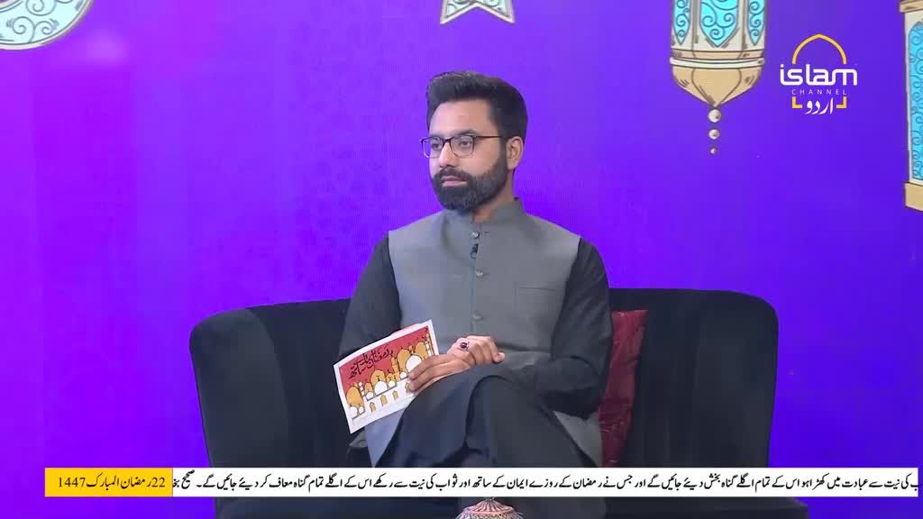 A man sits on a dark couch, holding a small, illustrated booklet. He wears a grey vest over a black tunic, and his beard is neatly trimmed. The backdrop is a vibrant purple, with Islamic motifs and the Islam Channel Urdu logo visible. A man sits on a dark couch, holding a small, illustrated booklet. He wears a grey vest over a black tunic, and his beard is neatly trimmed. The backdrop is a vibrant purple, with Islamic motifs and the Islam Channel Urdu logo visible.