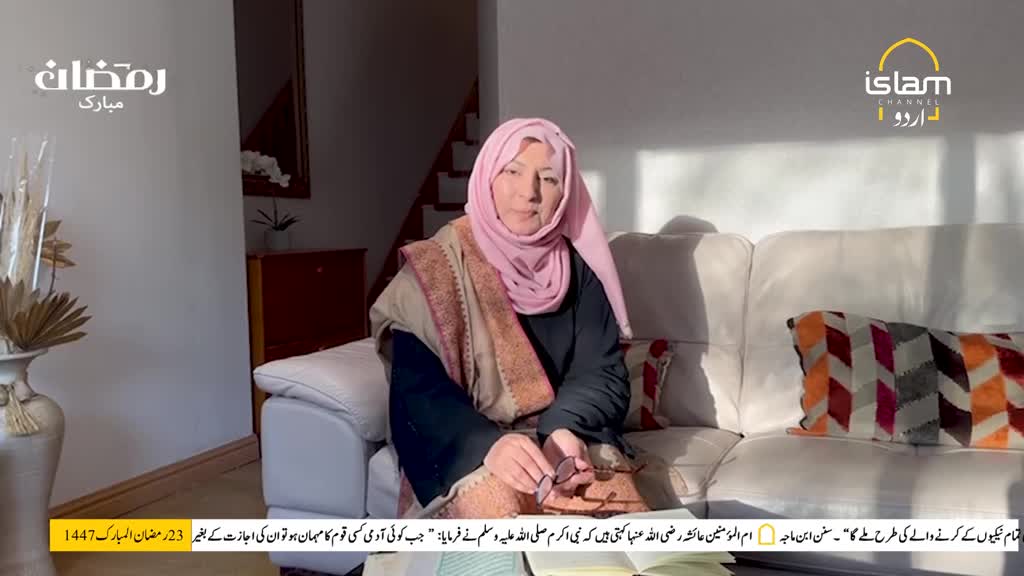 A woman in a pink hijab sits on a white sofa, holding glasses. Sunlight streams into the room, illuminating the scene. A woman in a pink hijab sits on a white sofa, holding glasses. Sunlight streams into the room, illuminating the scene.
