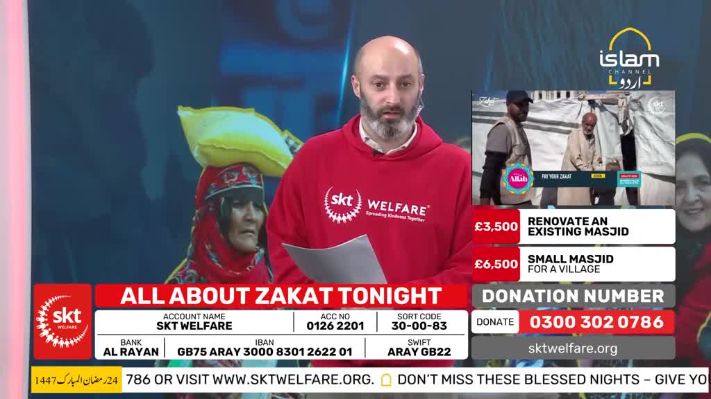 A man in a red hoodie stands on a stage, speaking into a microphone. To his left, a woman with a yellow bundle on her head looks out. On the right, a screen shows two men working near a tent. A man in a red hoodie stands on a stage, speaking into a microphone. To his left, a woman with a yellow bundle on her head looks out. On the right, a screen shows two men working near a tent.