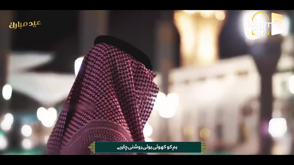 A man wearing a red and white checkered ghutra turns his back to the camera, his head bowed. In the background, the illuminated architecture of a mosque glows softly against the night sky. A man wearing a red and white checkered ghutra turns his back to the camera, his head bowed. In the background, the illuminated architecture of a mosque glows softly against the night sky.
