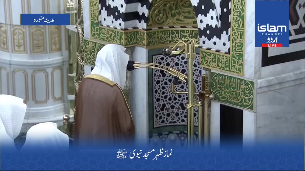 A man in a brown robe and white head covering stands facing a microphone stand. The Islam Channel Urdu logo is visible in the upper right corner.